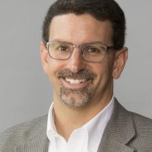 professional headshot of man in gray coat